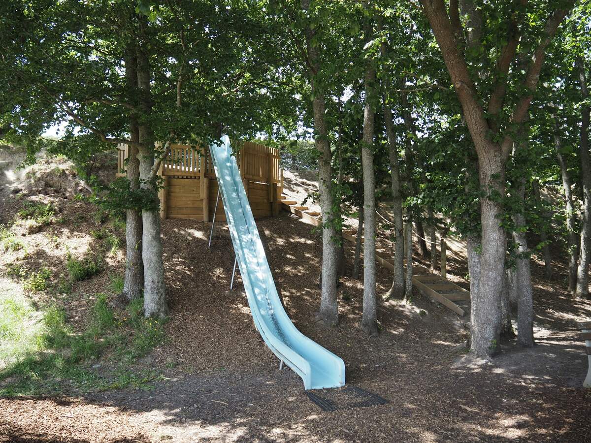 A slide from a wooden play fort onto a wood-chip slope