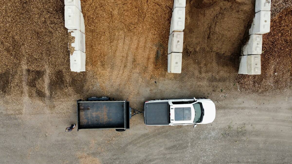A pickup and trailer beside bark bays at a bulk landscape yard